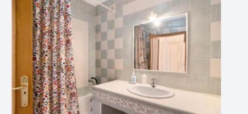 a bathroom with a sink and a mirror and a shower curtain at Apartment Moni Cabanas de Tavira Algarve in Cabanas de Tavira
