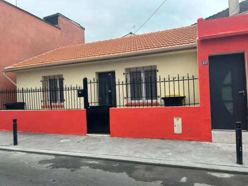 ein rotes und weißes Haus mit einem schwarzen Zaun in der Unterkunft Studio proche Stade de France in Saint-Denis