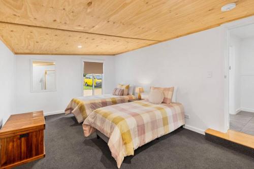 a bedroom with two beds and a wooden ceiling at Coastal Cottage Warrnambool in Warrnambool