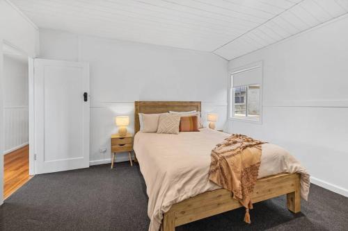 a white bedroom with a large bed and a window at Coastal Cottage Warrnambool in Warrnambool
