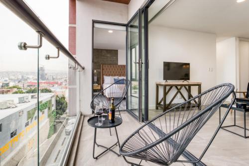 Habitación con 2 sillas y balcón con mesa. en ULIV Revolución Tijuana en Tijuana