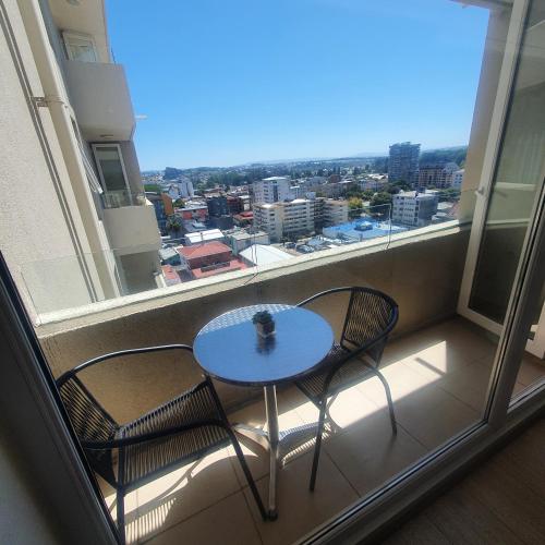 a table and two chairs on a balcony with a window at Departamento Centro Osorno in Osorno