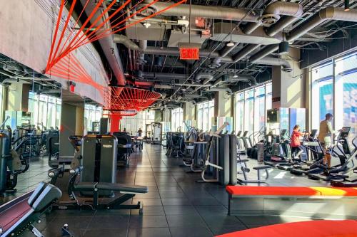 a gym with lots of cardio equipment and people in it at Sky-Rise Apartments in Los Angeles