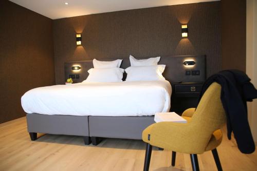 a bedroom with a large white bed and a chair at Best Western Plus Le Fairway Hotel & Spa Golf d'Arras in Anzin-Saint-Aubin