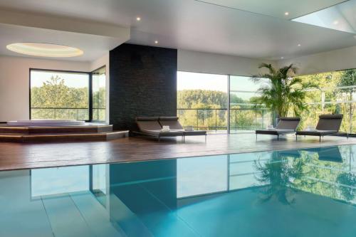 a swimming pool in a house with chairs and windows at Best Western Plus Le Fairway Hotel & Spa Golf d'Arras in Anzin-Saint-Aubin