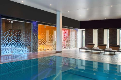 a swimming pool with chairs in a building at Best Western Plus Le Fairway Hotel & Spa Golf d'Arras in Anzin-Saint-Aubin