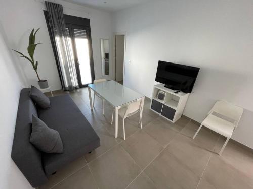 a living room with a couch and a table and a television at Encantador Apartamento en Lebrija in Lebrija