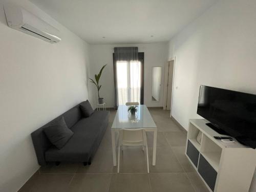 a living room with a couch and a table and a television at Encantador Apartamento en Lebrija in Lebrija