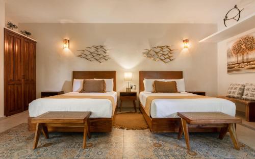 a hotel room with two beds and two tables at Le Muuch Hotel Boutique in Valladolid