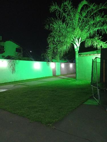 a green fence with a palm tree in a yard at night at Casa Temporada BV Capitolio in Capitólio