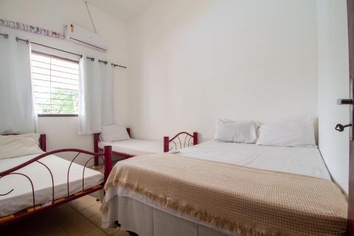 a white room with two beds and a window at Casa em Porto, piscina e 5 qrts in Porto De Galinhas