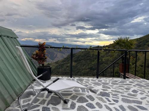 a chair on a balcony with a view of a mountain at Entre Verdes Hotel & Glamping in Medellín