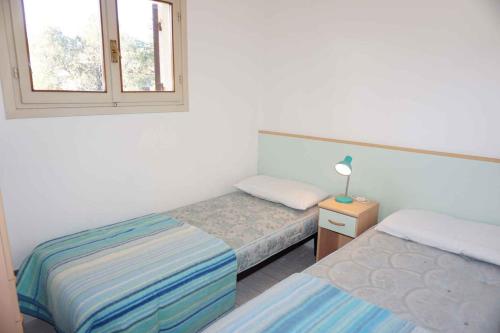 - une chambre avec 2 lits et une fenêtre dans l'établissement Holiday Homes in Porto Santa Margherita 43919, à Porto Santa Margherita