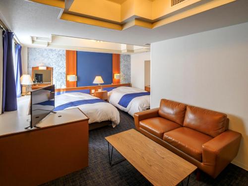 una camera d'albergo con divano e letto di Airline Hotel a Miyazaki