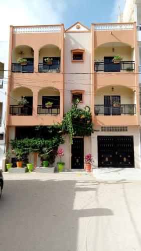 un grand bâtiment avec des plantes en pot devant lui dans l'établissement Délices Chez l'Habitant Diack, à Dakar