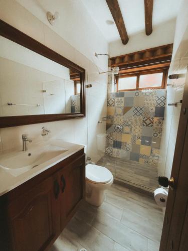 a bathroom with a sink and a toilet and a shower at Posada María del Carmen in Ráquira
