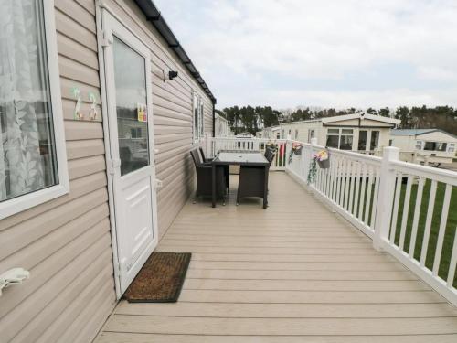 een houten terras met een tafel aan de zijkant van een huis bij flower pot retreat in Scarborough