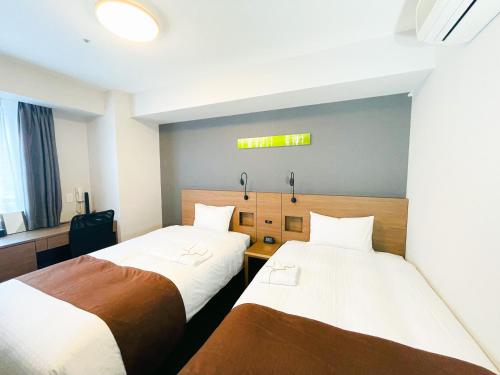 um quarto com duas camas e uma placa na parede em Smile Hotel Premium Sapporo Susukino em Sapporo