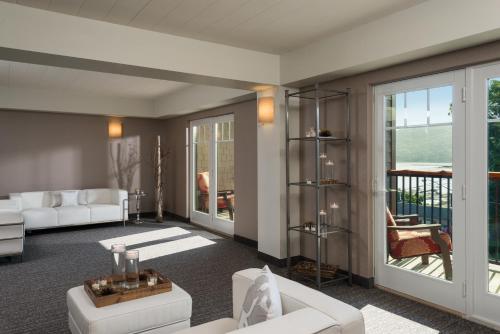 a living room with white furniture and a balcony at Courtyard by Marriott Lake George in Lake George