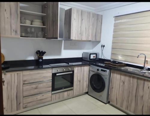 a kitchen with wooden cabinets and a washing machine at LV Appartment x Airport Residential Area in Accra