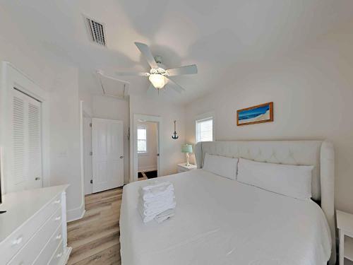 a white bedroom with a white bed and a ceiling fan at Bungalows at Seagrove #132 - Kruks Fanta Sea in Seagrove Beach