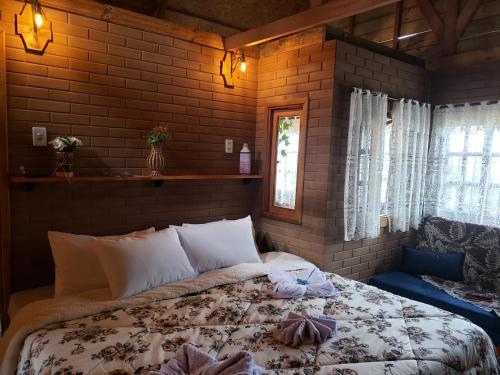 uma cama num quarto com uma parede de tijolos em Pousada Grom's Village em Campos do Jordão