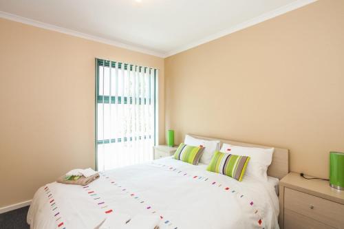 a bedroom with a large white bed with a window at Anglesea River Apartment On Noble in Anglesea