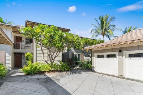a house with white garage doors and palm trees at Mauna Lani Palm Villas D-2 Corner Unit Historic View in Waikoloa