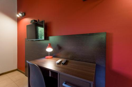 a red wall with a desk with a lamp on it at Solar Selvana - Casas de montaña in Villa La Angostura