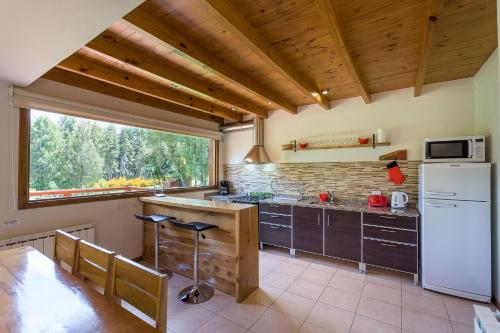 a kitchen with a white refrigerator and a window at Solar Selvana - Casas de montaña in Villa La Angostura