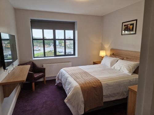 Habitación de hotel con cama, escritorio y ventana en Home Inn, en Athlone