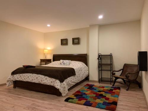 a bedroom with a bed and a chair and a rug at HOBU MONTAÑA in La Calera