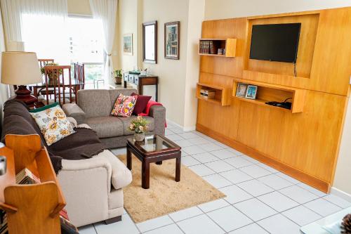 een woonkamer met een bank en een tv bij Praia da Costa 2 Quartos com Suite Clássico in Vila Velha