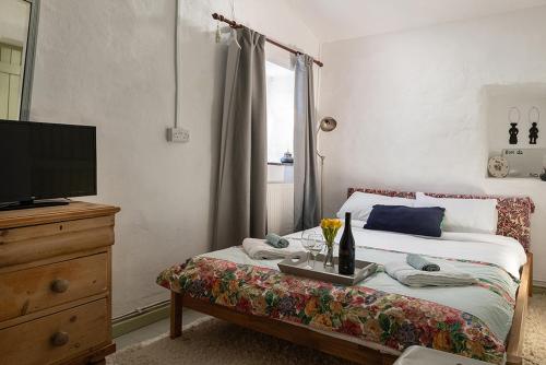1 dormitorio con 1 cama con TV y vestidor en Cobweb Cottage en Waenfawr