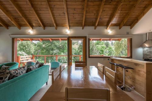 a living room with chairs and tables and windows at Solar Selvana - Casas de montaña in Villa La Angostura