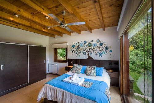 a bedroom with a bed with blue sheets and a tree mural at Solar Selvana - Casas de montaña in Villa La Angostura