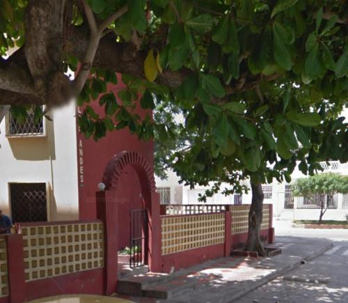 a red fence in front of a building with a tree at Apartamento Amoblado in Barranquilla