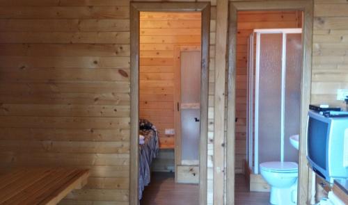 a bathroom in a log cabin with a toilet at Camping La Eliza in Lanzahita