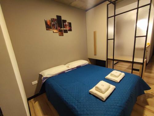 1 dormitorio con 1 cama azul y 2 toallas en Departamento - Salta Capital sm - Edificio Usina en Salta