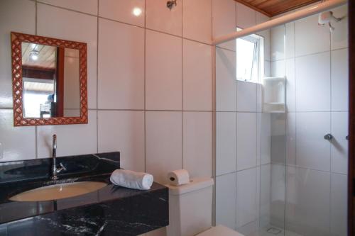 a bathroom with a sink and a shower and a mirror at Pousada Beira Mar in Ilha do Mel