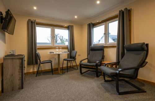 a waiting room with chairs and a table and windows at Rosewood Cottage in Fort William