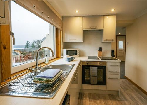 a kitchen with a sink and a window at Rosewood Cottage in Fort William