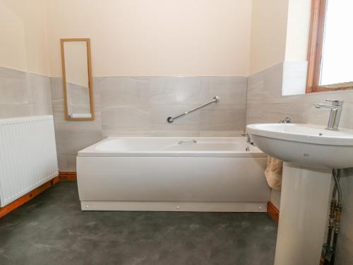 een badkamer met een wit bad en een wastafel bij Arwelfa in Valley