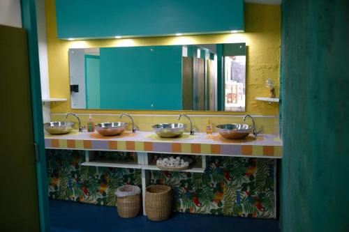 a bathroom with three sinks and a large mirror at Ragamuffin Hostel in Kingston