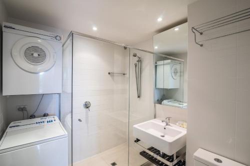 a white bathroom with a shower and a sink at Noosa Harbour Resort in Noosa Heads