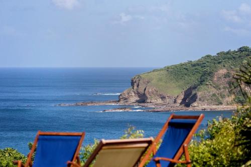 a view of the ocean from a beach with two chairs at Casa Oli Mar in San Juan del Sur