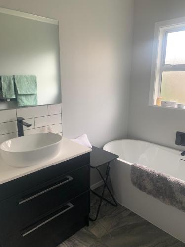 a bathroom with a white tub and a sink and a bath tub at Robert ST Newlands in Wellington