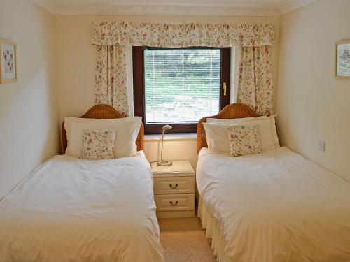 two beds in a room with a window at The Garden Apartment in Saint Columb Major