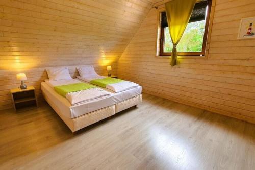 a bedroom with a bed in a wooden room at Comfortable cottages, very close to the sea, G ski in Gąski