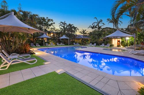 a swimming pool with chairs and umbrellas in a resort at Noosa Harbour Resort in Noosa Heads